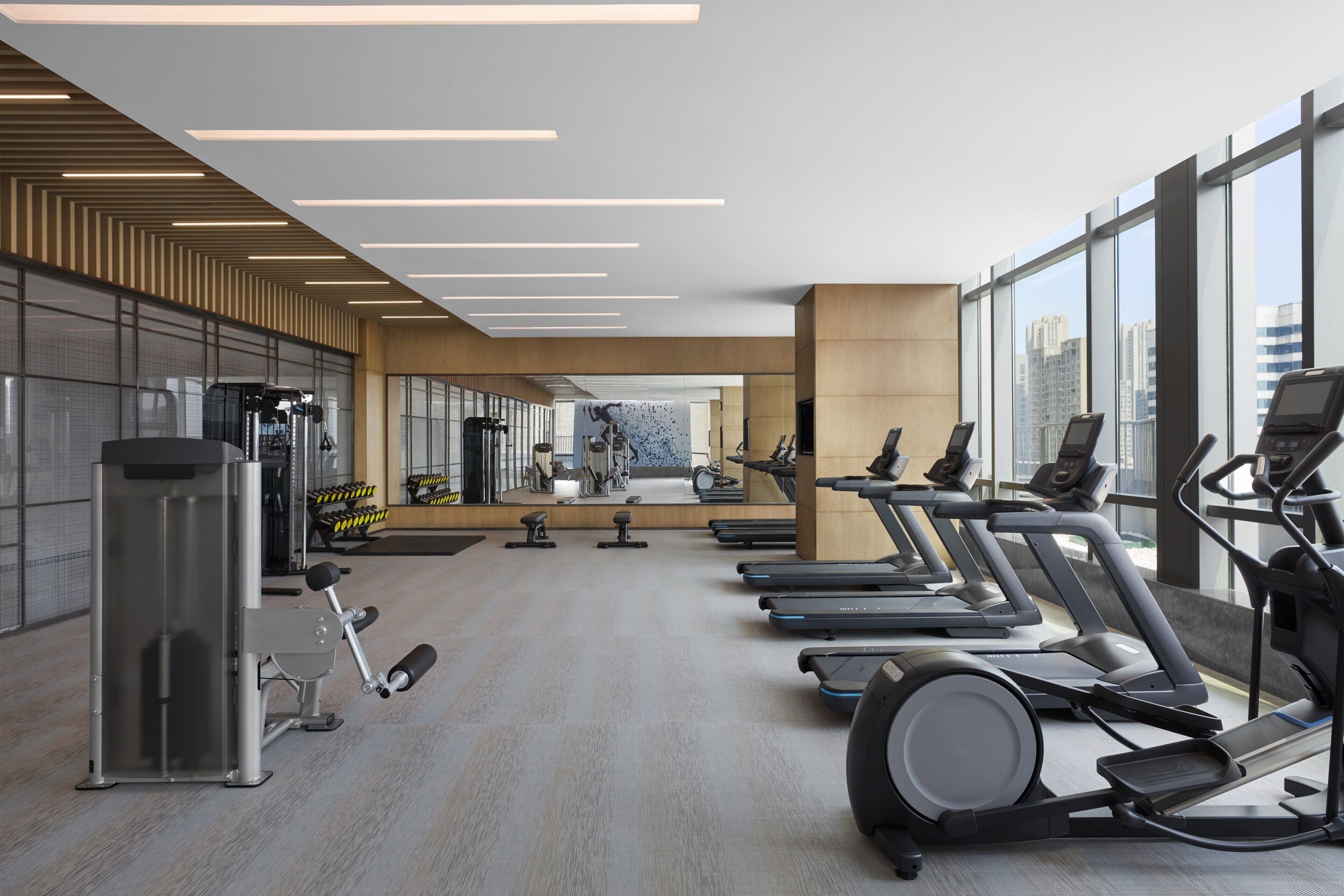 Un gimnasio moderno con cintas de correr, elípticas y equipos de pesas.
