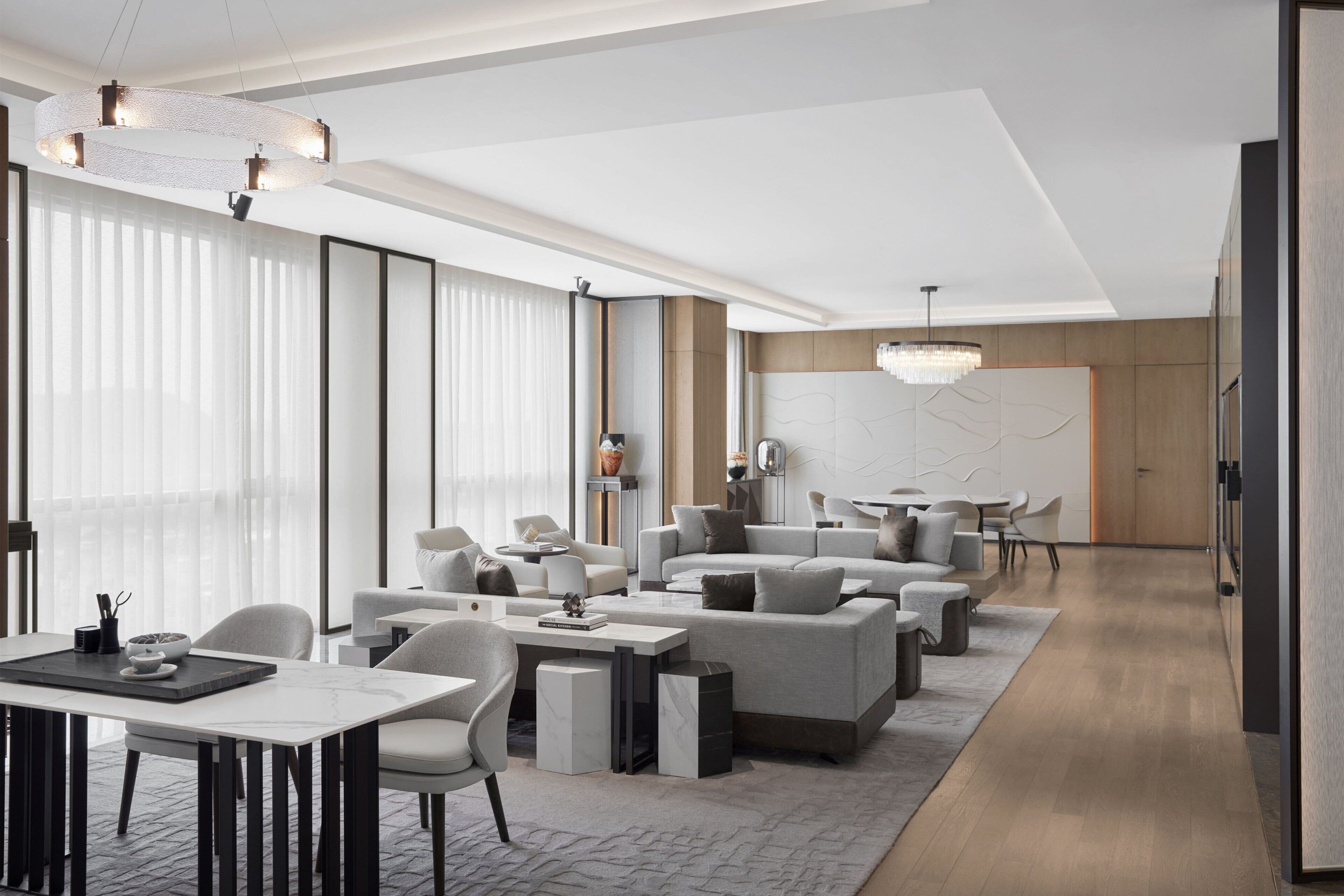 A modern hotel lobby with a seating area, a dining table, and a reception desk.