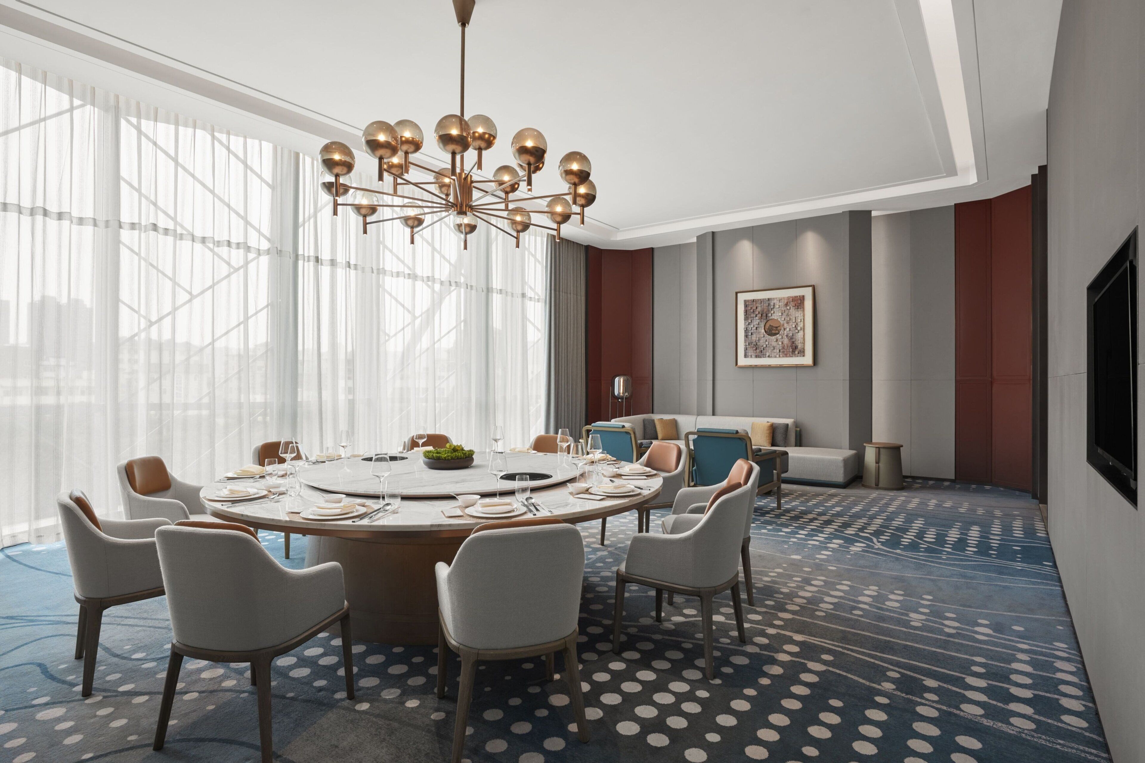 A modern conference room with a round table, chairs, and a chandelier.
