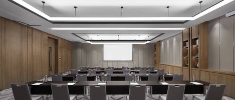 Un salón de conferencias con una larga mesa, sillas, una pantalla de proyector y piso alfombrado.