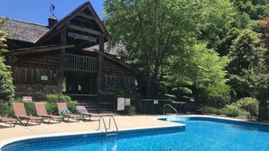 Un'area piscina con lettini e un edificio in legno con un cartello che riporta la scritta 'THE VILLAGE'.