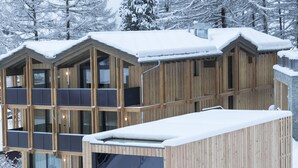 Una cabaña de madera con varios balcones, rodeada de árboles cubiertos de nieve.