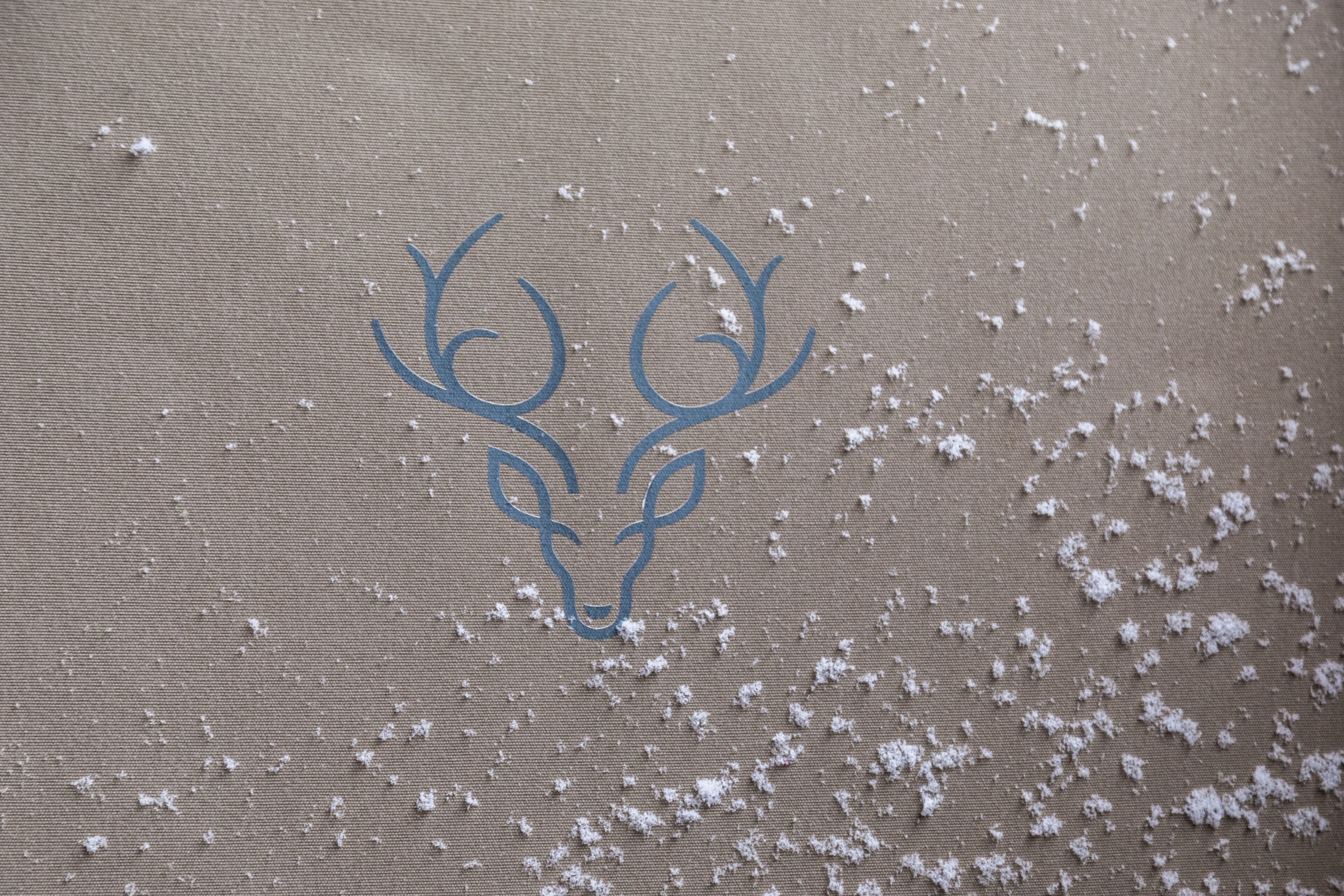 A logo of a deer head on a textured surface.