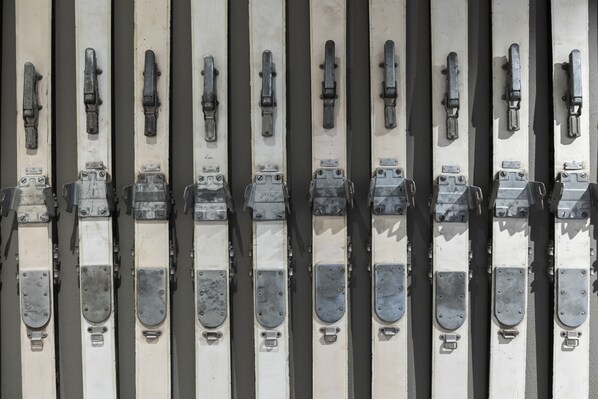 A row of skis with metal bindings and straps, likely for rental or sale. - Nomad by CERVO Mountain Resort (Zermatt)