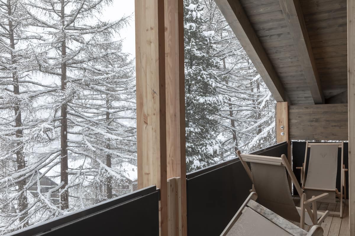 A wooden balcony with a view of snow-covered trees.