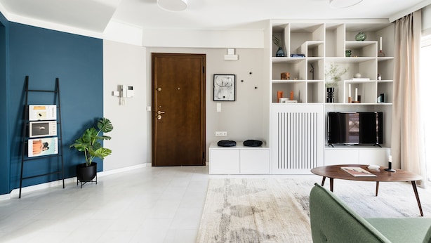 A modern living room with a blue accent wall, a wooden door, a white console table, a round coffee table, and a green armchair. - Iconic 1BR Apartment in Koukaki (Athens)