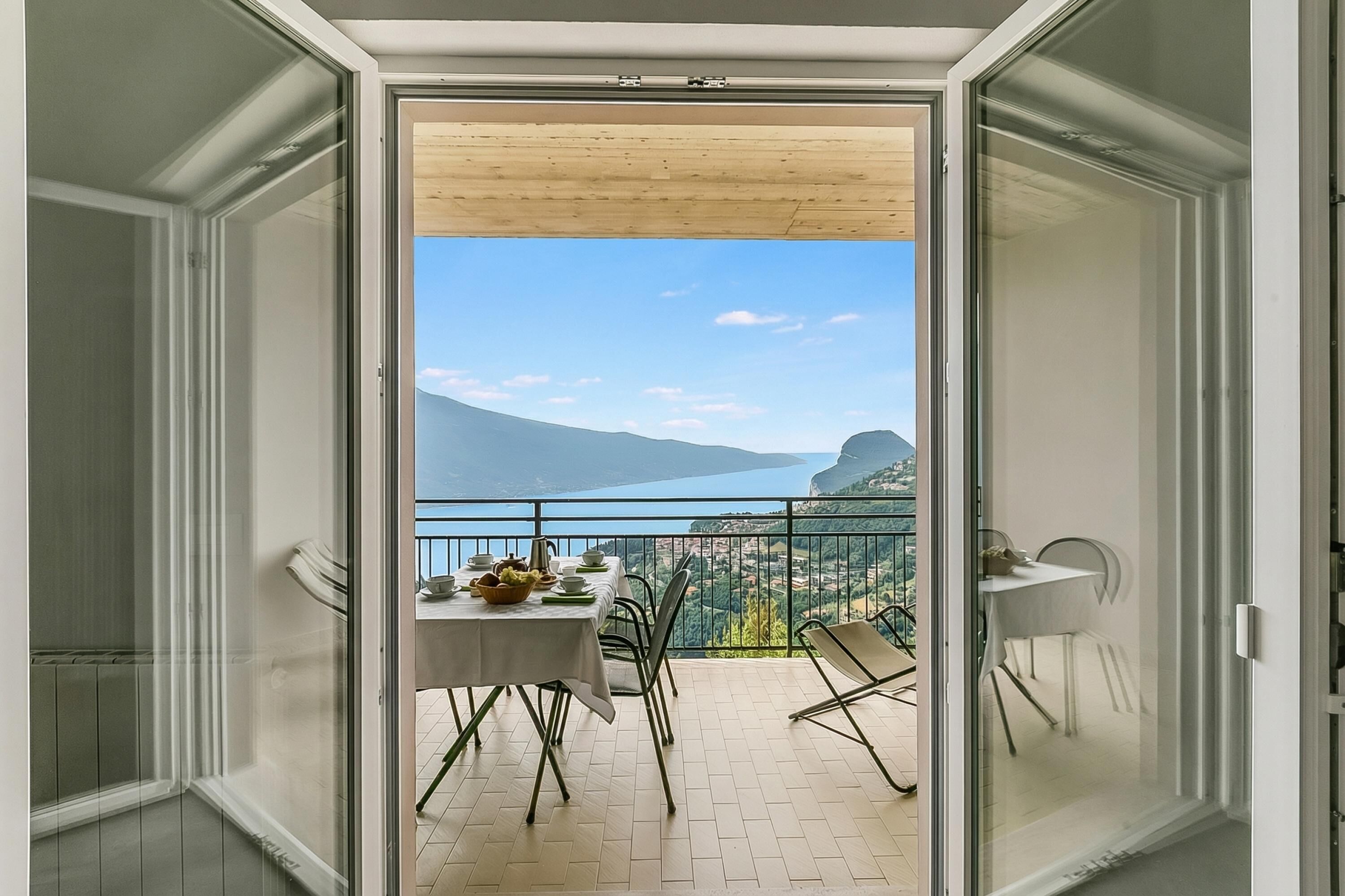 Een balkon met een eettafel, stoelen en uitzicht op een bergachtig landschap.