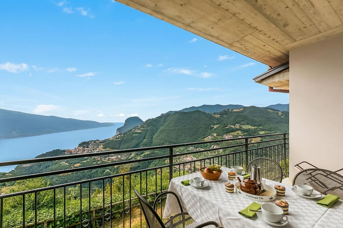 Un balcon avec une table dressée pour le thé, d’où l’on peut admirer un lac et des montagnes.