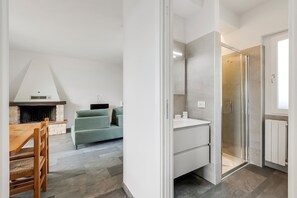 Uma sala de estar moderna com lareira, um sofá e uma mesa de jantar.