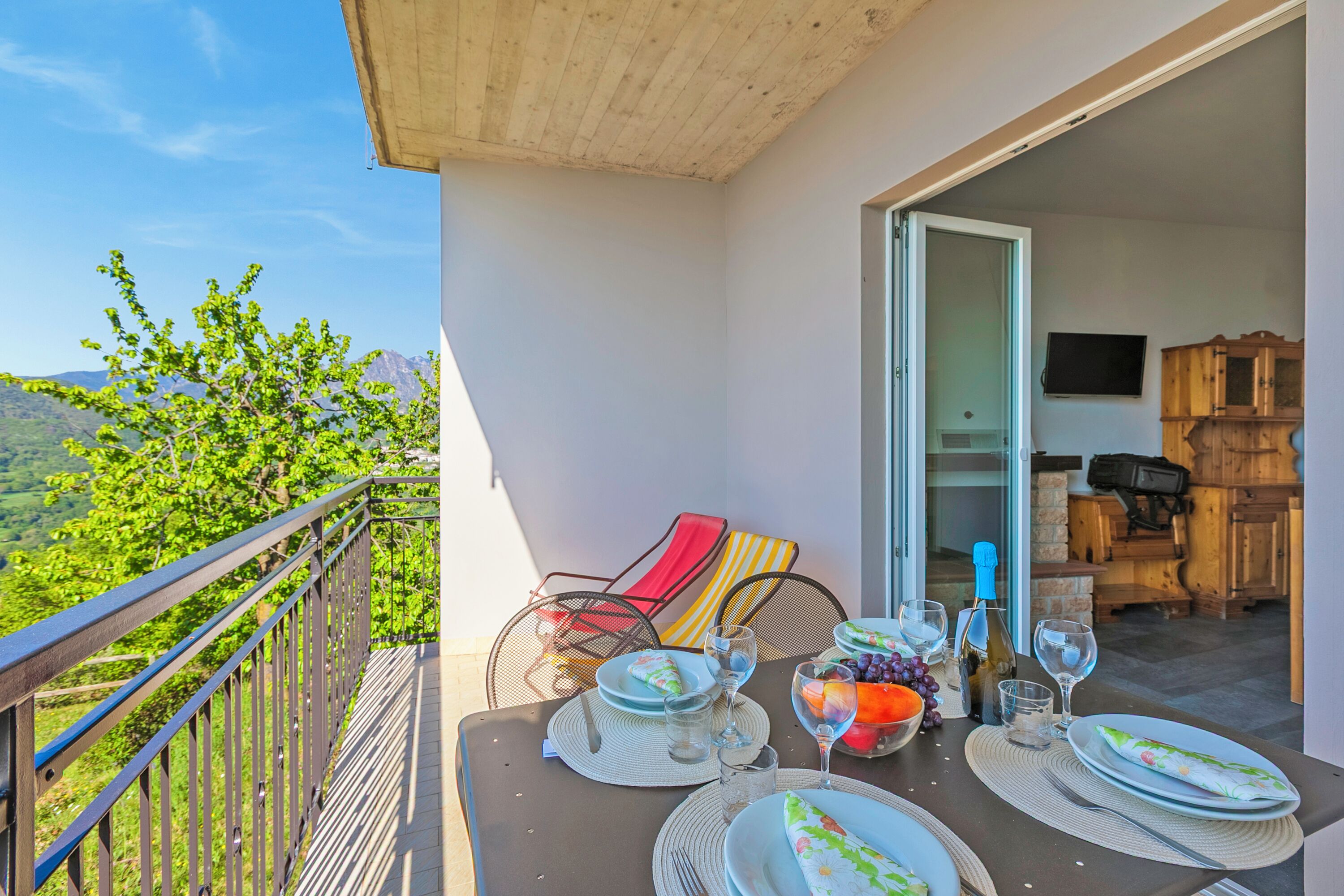 Un balcon avec une table dressée pour deux personnes, une chaise et une vue sur les montagnes.