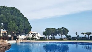 En swimmingpool med ett klart, blått vatten och en omgivande poolterrass som är belagd med plattor.