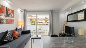 A modern living room with a grey sofa, a coffee table, a TV, and a balcony with outdoor furniture. - GO2TENERIFE Apart'Lotus Pool + beach 400m (Arona)