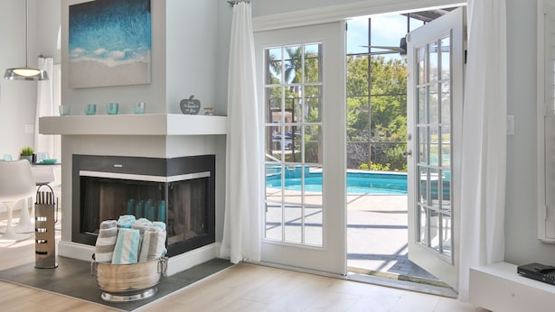 Una sala de estar moderna con chimenea, vista a la piscina y puerta corrediza de vidrio.