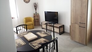 Un coin repas comprenant une table ronde, des chaises, un téléviseur et un meuble en bois.