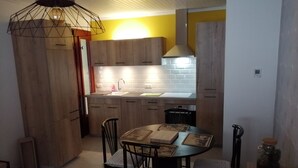 Une cuisine compacte avec des meubles en bois, un évier encastré et un coin repas comprenant une table ronde et des chaises.