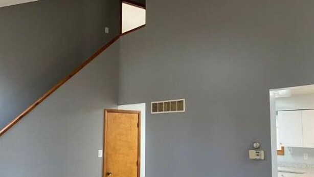 A room with a wooden door, a small window, and a light switch on the wall.