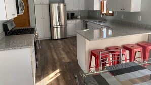 A modern kitchen with white cabinets, stainless steel appliances, and a granite countertop.
