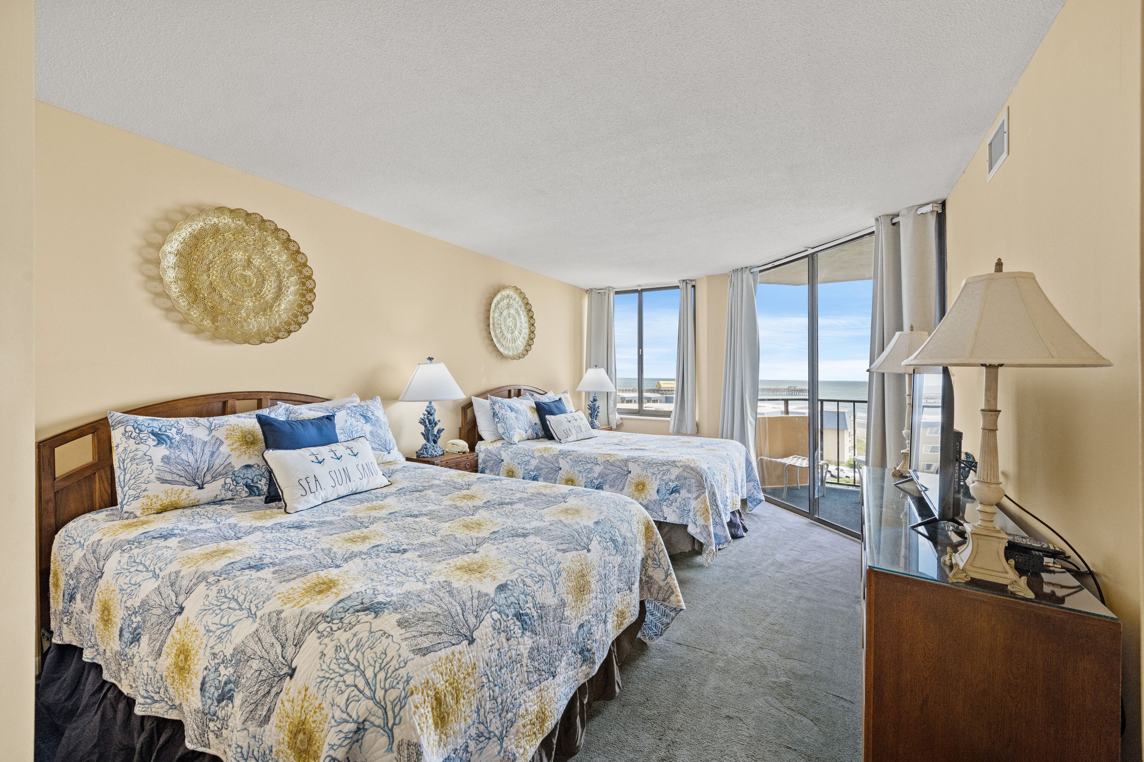A hotel room with two beds, a large window, and a balcony.