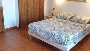 A bedroom with a large bed, wooden wardrobe, and a painting on the wall. - Charming village house in the heart of the Luberon (Pierrevert)