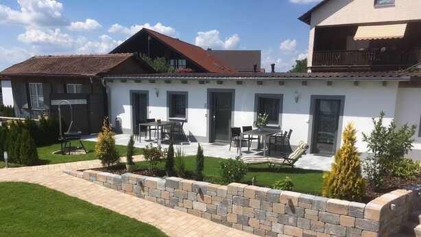 A residential building with a patio area, outdoor seating, and a stone retaining wall. - Holiday apartment North (WA325) (Wackersdorf)