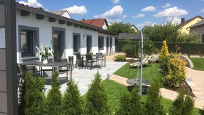 A modern house with a patio area featuring outdoor furniture and a swing chair. - Holiday apartment North (WA325) (Wackersdorf)