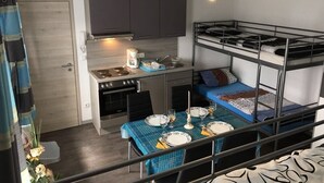 A compact room with a bunk bed, a kitchenette, and a dining area. - Holiday apartment North (WA325) (Wackersdorf)