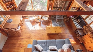 Un intérieur spacieux en bois, comprenant un canapé, une table à manger et des chaises, une cheminée et une bibliothèque.