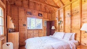Une chambre dans une cabane en bois, avec un lit, un bureau et une chaise.