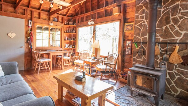 Un intérieur de chalet chaleureux avec une cheminée en pierre, des meubles en bois et une grande fenêtre.