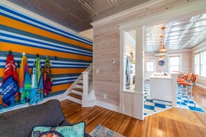 Un interior moderno con una escalera, una zona de cocina y un espacio de descanso con sombrillas coloridas.