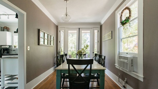 A dining area with a table and chairs, a kitchen in the background, and a view through the windows. - Iconic Modern Farmhouse+walkable+views+BBQ (San Luis Obispo)