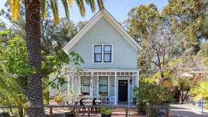 A two-story house with a gabled roof, a front porch with a railing, and a black front door. - Iconic Modern Farmhouse+walkable+views+BBQ (San Luis Obispo)