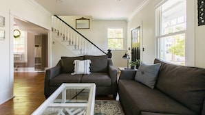 A living room with two couches, a staircase, and a large window. - Iconic Modern Farmhouse+walkable+views+BBQ (San Luis Obispo)