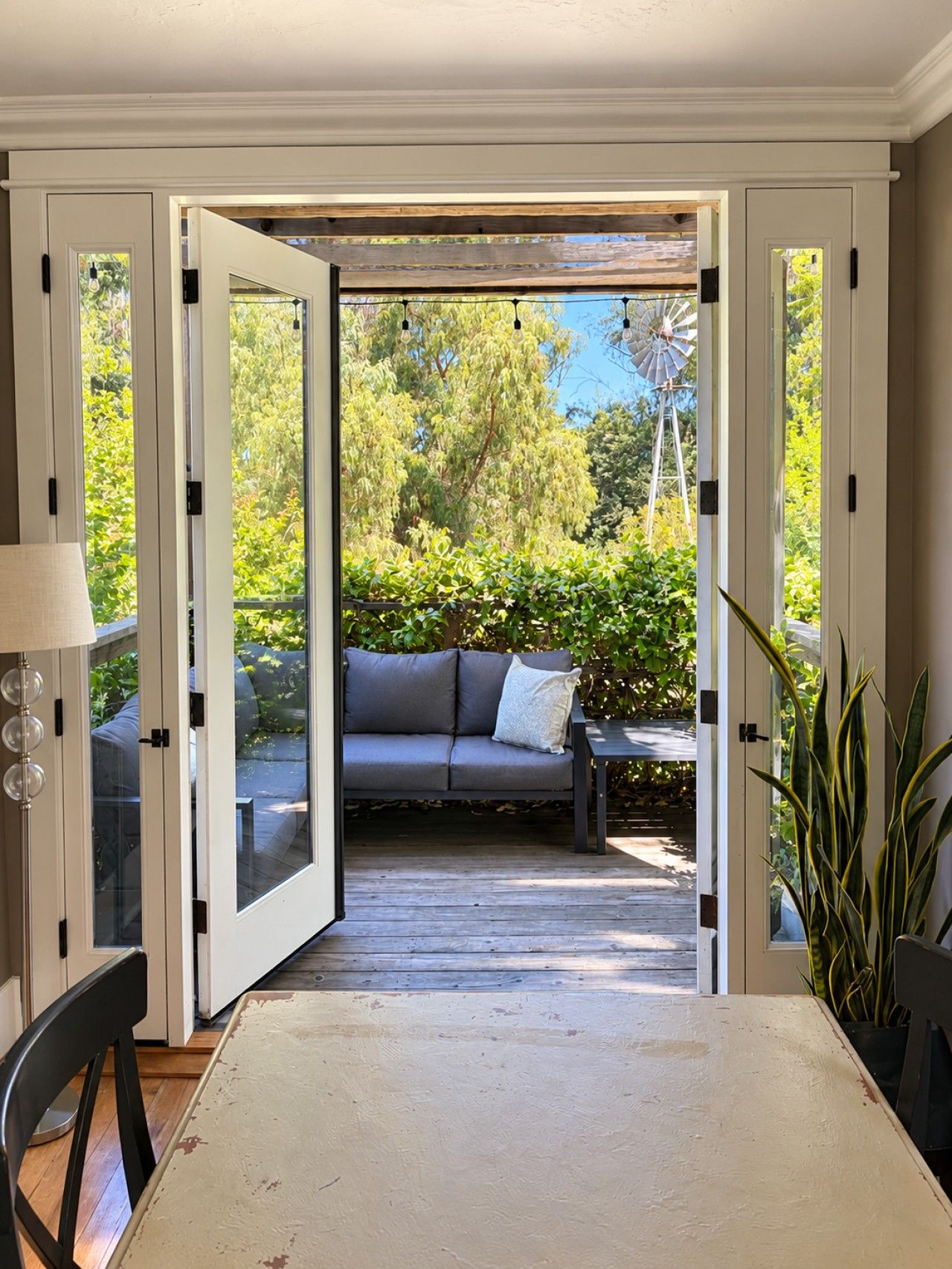 An open doorway leading to an outdoor seating area with a sofa and a table.
