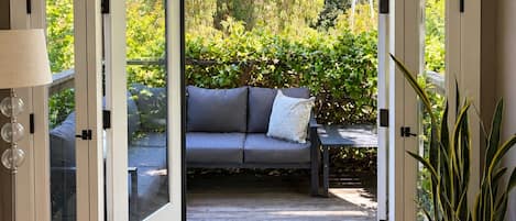 An open doorway leading to an outdoor seating area with a sofa and a table.