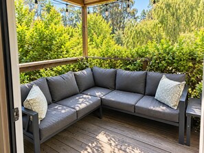 A wooden deck with a gray sectional sofa and two pillows.