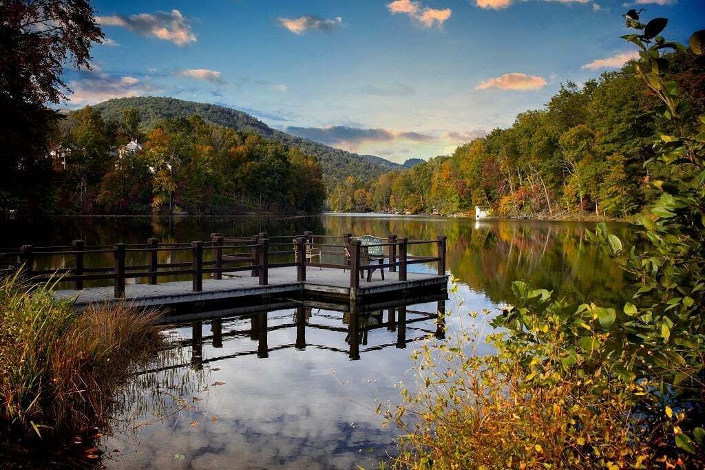 A wooden dock extending into a calm lake surrounded by dense forest.