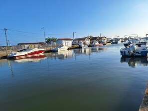 Een jachthaven met verschillende boten afgemeerd, een houten omheining en kleine gebouwen met rode daken.