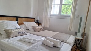 Een hotelkamer met twee bedden, een elektrische kachel en een raam met gordijnen.