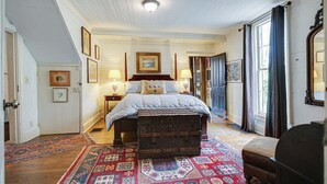 A bedroom with a bed, a chest of drawers, a rug, and framed pictures on the walls.