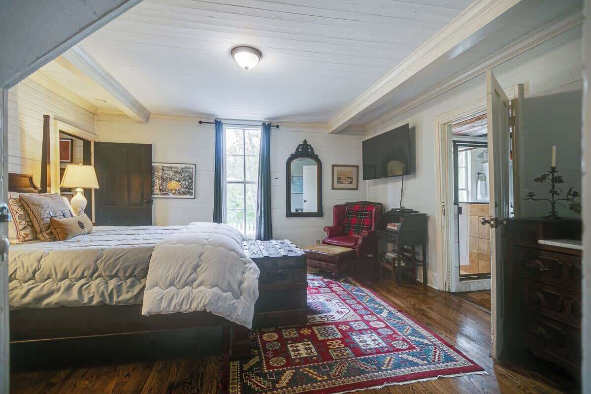 Un dormitorio con cama, cómoda, silla, espejo y televisor.