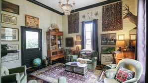 A traditional room with a fireplace, a globe, a wooden cabinet, and a deer head decoration.