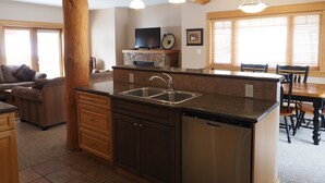 A spacious kitchen with a central island, wooden beams, and pendant lighting. - 4 BD/3BA Redstone Chalets E (Rossland)