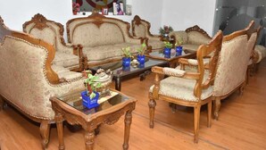 A traditional living room with ornate wooden furniture, a glass coffee table, and a floral painting on the wall. - Remarkable 6-bedroom Farmhouse in South Delhi (New Delhi)
