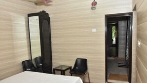 A hotel room with a bed, a mirror, two chairs, and a small table. - Remarkable 6-bedroom Farmhouse in South Delhi (New Delhi)