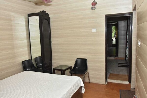 A hotel room with a bed, a mirror, two chairs, and a small table.