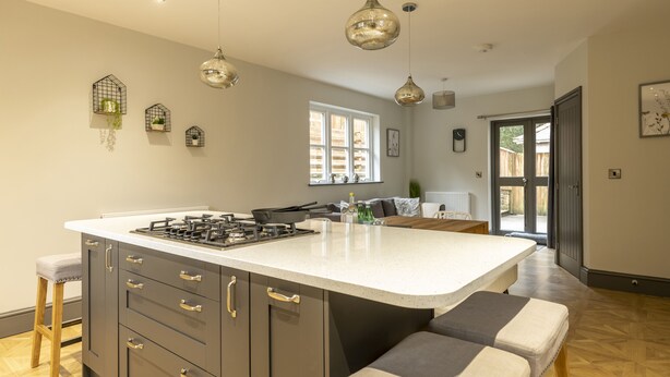 A modern kitchen with a large island, pendant lighting, and a view to the outside.