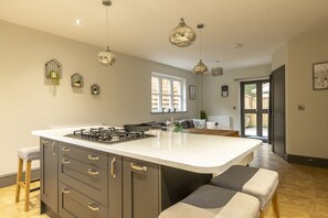 A modern kitchen with a large island, pendant lighting, and a view to the outside. - North Lodge (Lancaster)