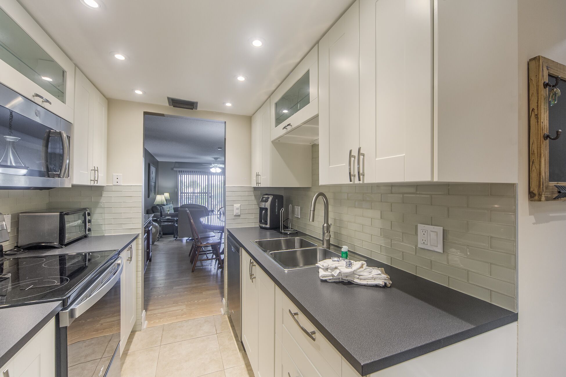 A modern kitchen with white cabinets, a black countertop, and stainless steel appliances.