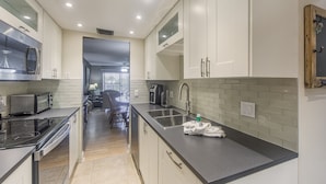 A modern kitchen with white cabinets, a black countertop, and stainless steel appliances.